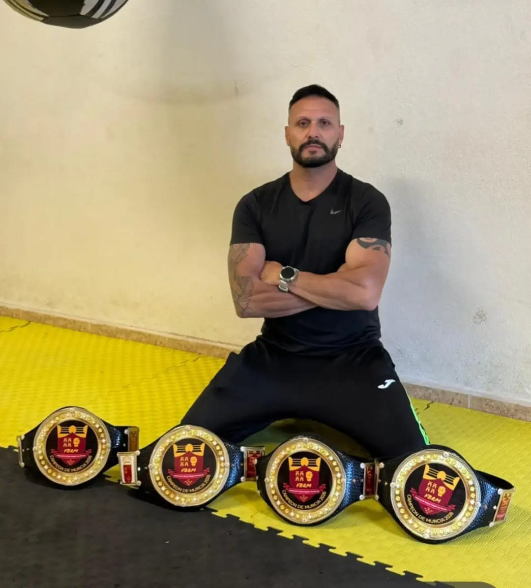 Retrato en el tatami junto a cuatro cinturones de boxeo