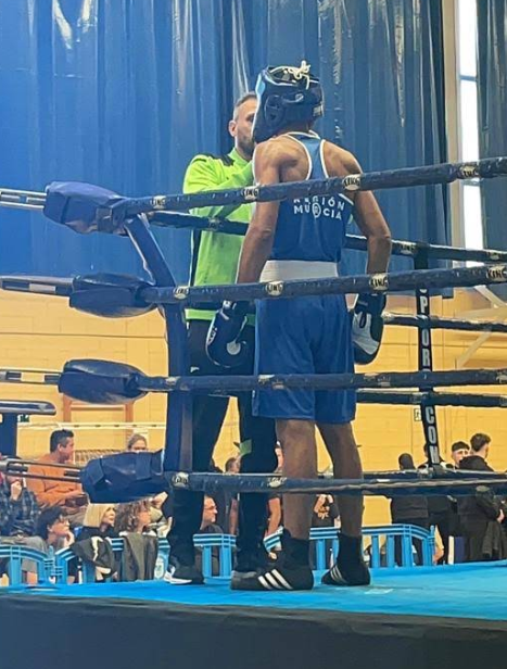 Boxeador con equipación azul en la esquina del ring junto a su entrenador